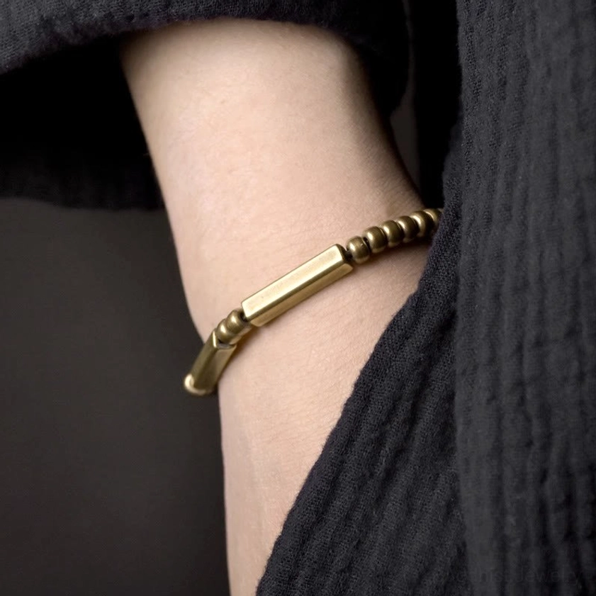 Worn copper wealth bracelet on wrist, minimalist design with black clothing, side view showing comfortable stretch fit