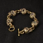 Handcrafted copper brass skull protection bracelet with 3D carved skull charms and toggle clasp, displayed on black fabric background - Buddhist spirituality jewelry