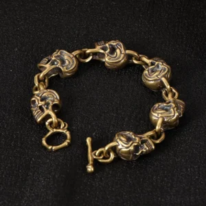 Handcrafted copper brass skull protection bracelet with 3D carved skull charms and toggle clasp, displayed on black fabric background - Buddhist spirituality jewelry