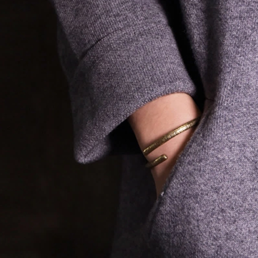 Copper buddhist cuff bracelet worn on wrist - adjustable open design with grey wool coat styling