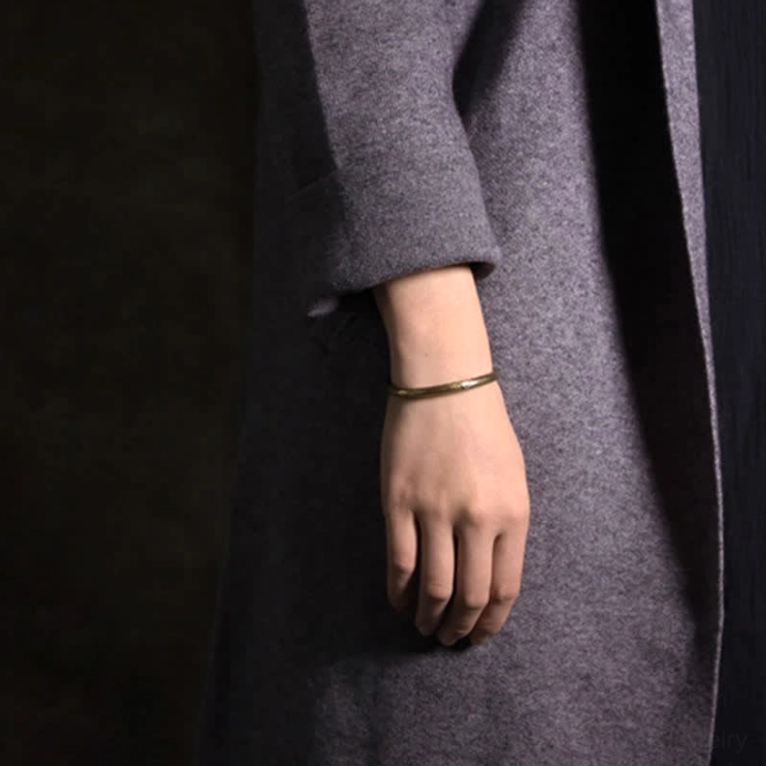Copper buddhist balance bracelet on wrist - side view worn with grey coat