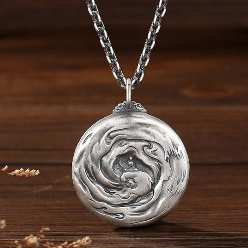 Reverse side of Buddhist copper pendant necklace showing swirl engravings with centered Buddha figure design