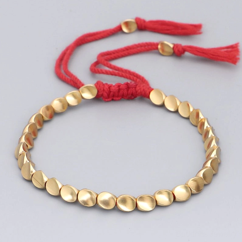 Copper healing bracelet with matte gold flat beads and red braided cord featuring decorative red woven knot