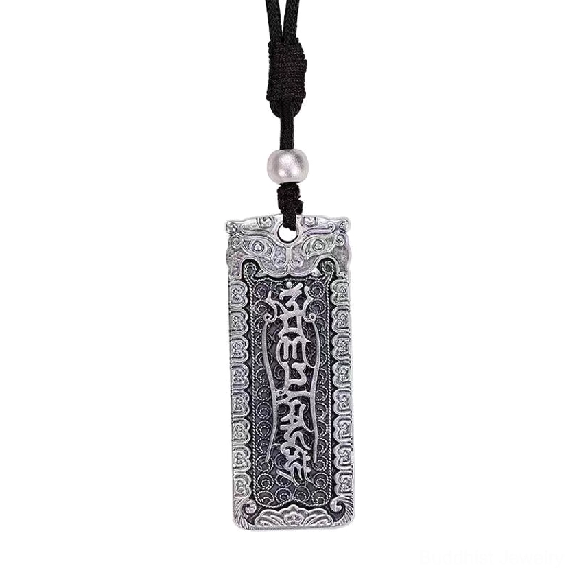 Buddhist mantra pendant hanging vertically on light background displaying carved Sanskrit scriptures and white decorative bead