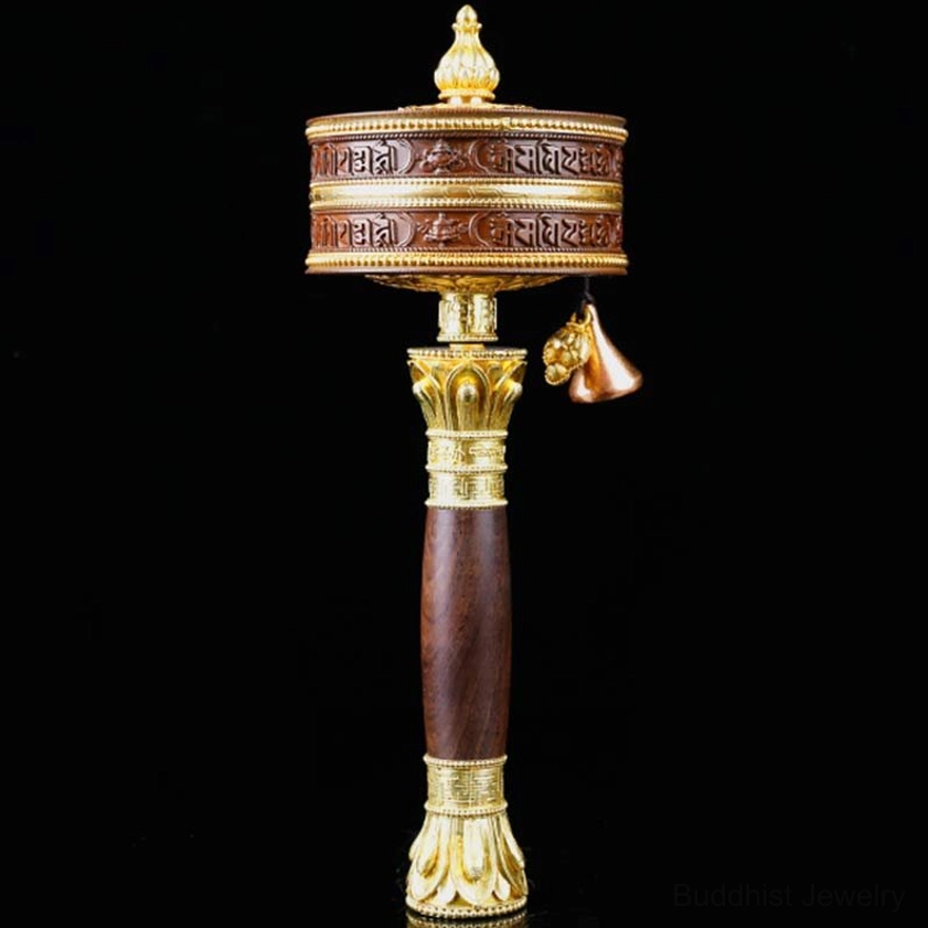Large copper Buddhist prayer wheel with golden lotus-style handle trim and decorative hanging bell on black background