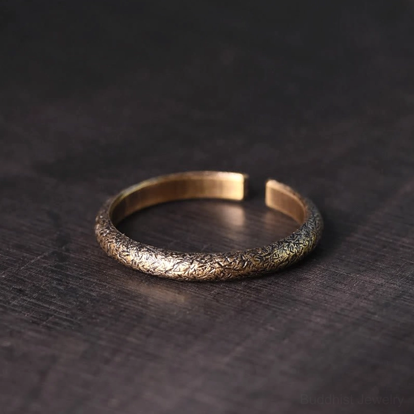 Single vintage copper Buddhist ring with gradient bronze finish and fine engraved grain pattern, top-down view