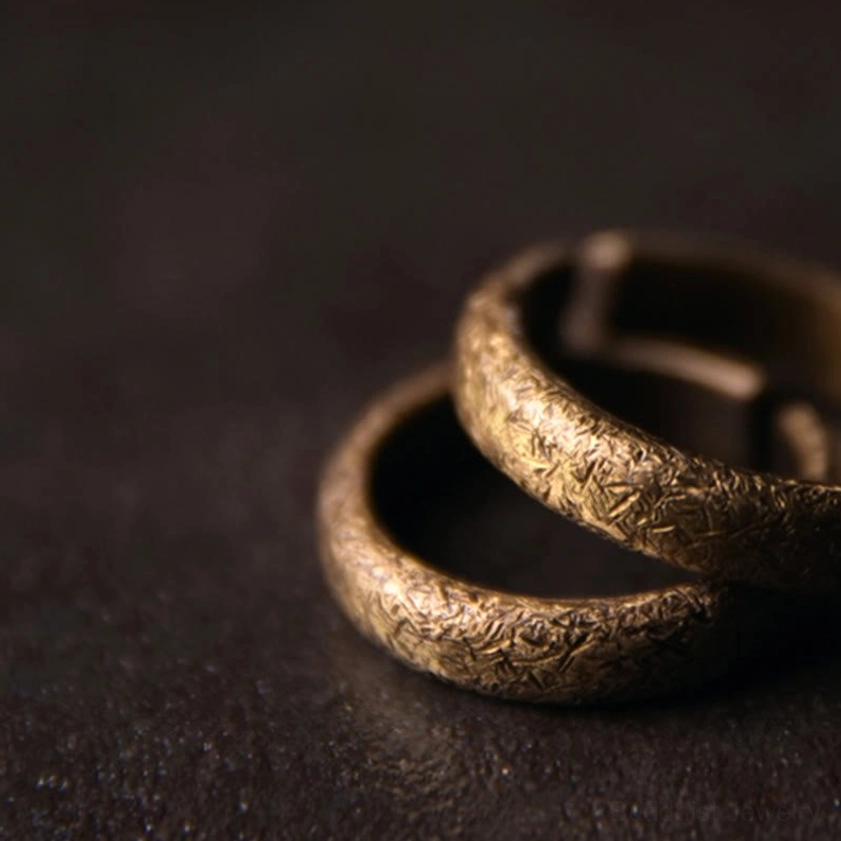 Two overlapping vintage copper Buddhist rings with weathered bronze patina, stacked close-up