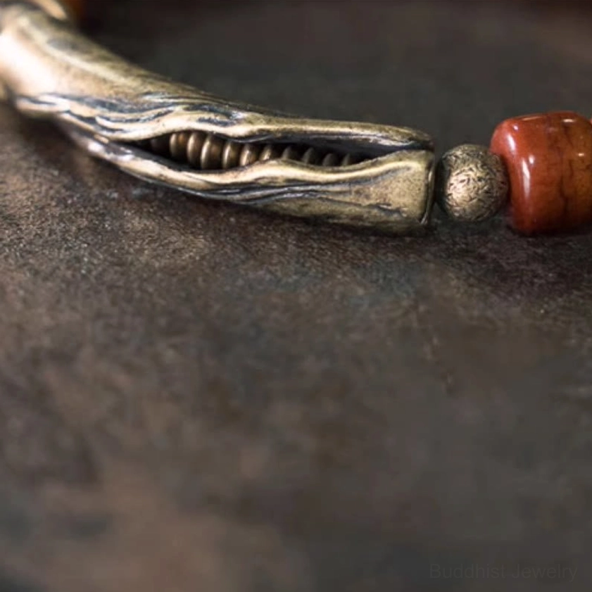 Detailed close-up of antique bronze textured clasp featuring internal coil detail and attached brown barrel bead on dark rustic background