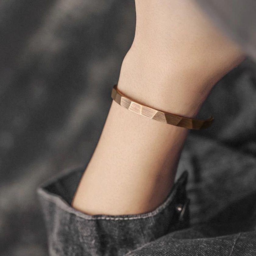Adjustable copper cuff bracelet close-up side detail showing thick brushed metal band with distinct faceted details