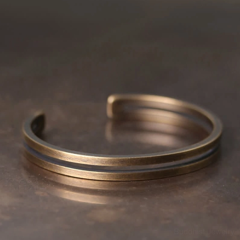 Side close-up of handcrafted copper cuff bracelet showing matte bronze finish and dual parallel bands
