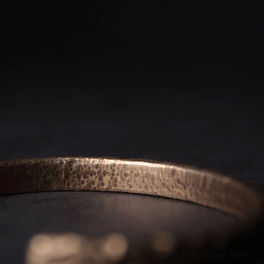 Single hammered copper open cuff bracelet side view displaying uneven textured surface and adjustable design