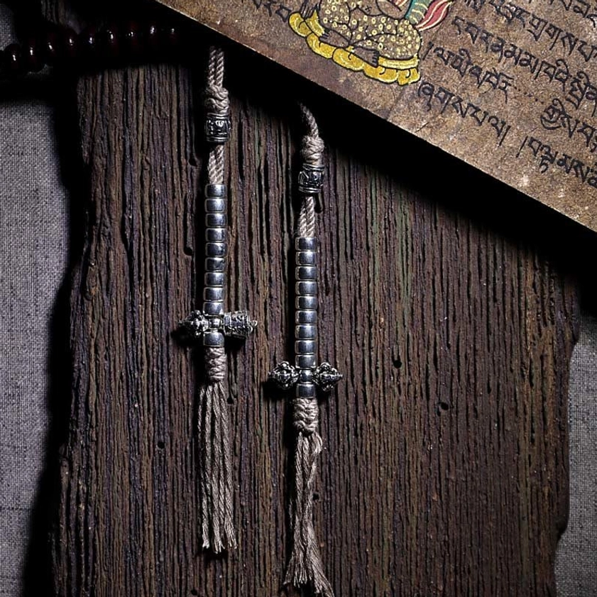 Copper dorje tassel charm and metal Buddhist accessories on weathered wood