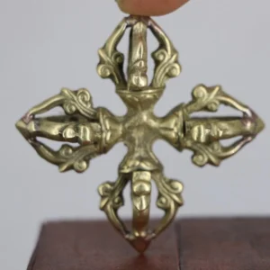 Handcrafted copper double dorje vajra held overhead close-up showing antique brass finish and carved scrollwork detail