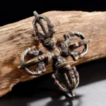 Handcrafted copper double dorje vajra overhead view on weathered wood - Buddhist thunderbolt symbol for spiritual power