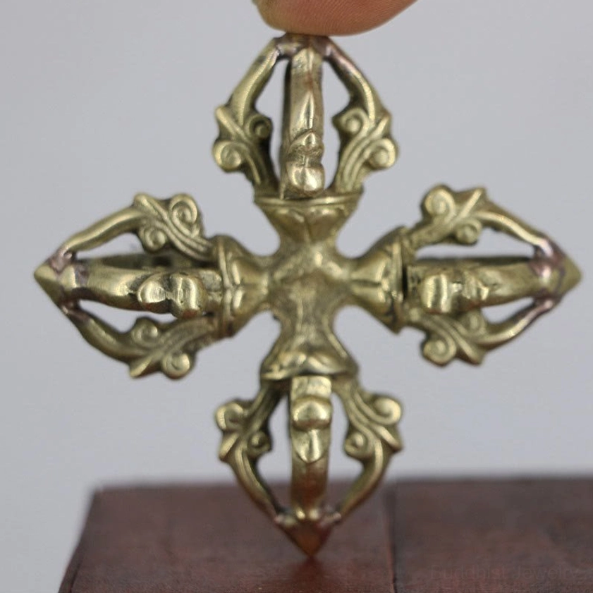 Handcrafted copper double dorje vajra held overhead close-up showing antique brass finish and carved scrollwork detail