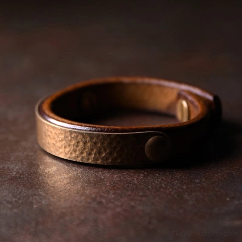 Handcrafted copper leather bangle bracelet displaying round dome rivet closure on vintage dark surface