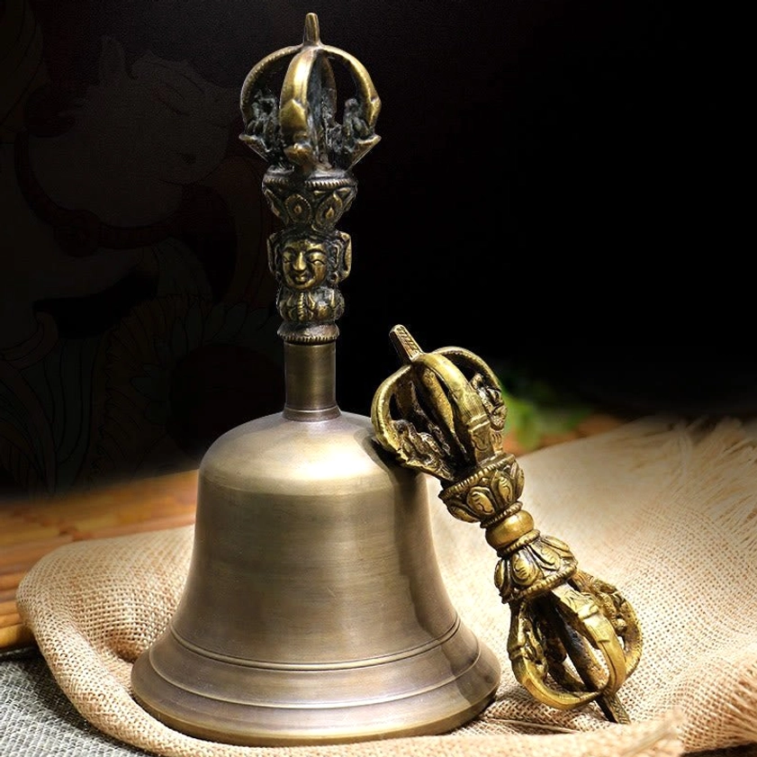 Handmade copper meditation bell and vajra dorje set displayed on natural linen and bamboo mat, top-down view showing complete ritual instrument pair