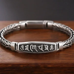 Copper Om Mani Padme Hum Buddhist bracelet with engraved mantra plaque and Vajra symbol, featuring vintage silver-tone braided chain on dark wooden background