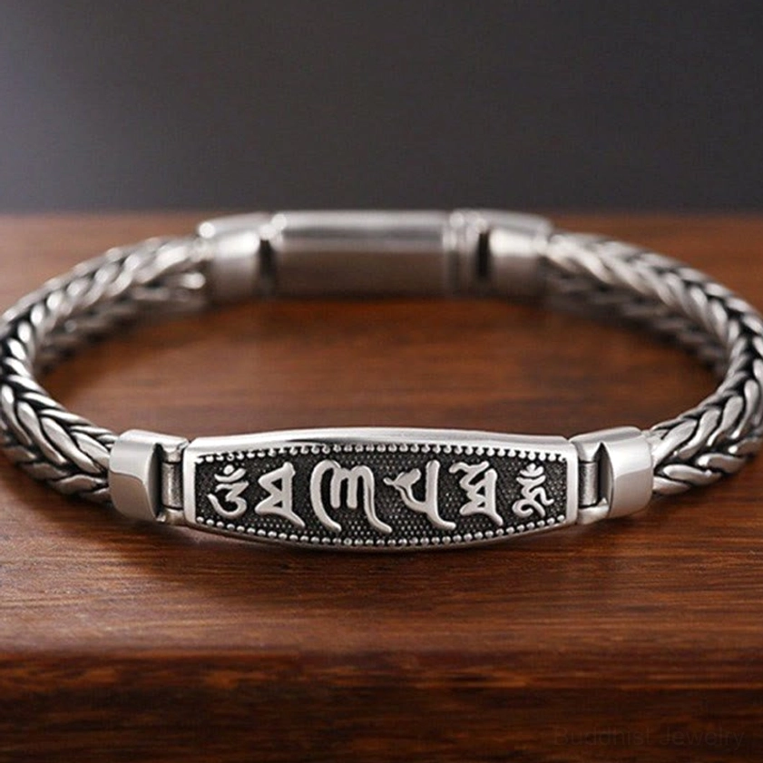 Copper Om Mani Padme Hum Buddhist bracelet with engraved mantra plaque and Vajra symbol, featuring vintage silver-tone braided chain on dark wooden background