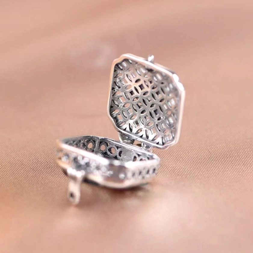 Hollow hinged prayer box locket - overhead flat lay showing open design and intricate metal texture for storing intentions