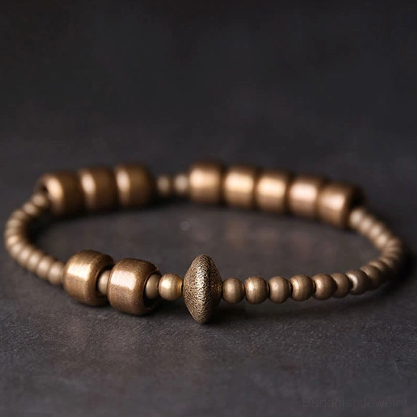 Copper brass Buddhist bracelet side close-up detail view with asymmetrical bead arrangement and brushed metal finish