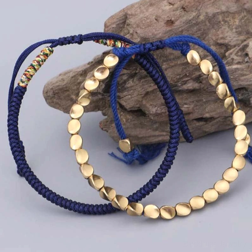 Adjustable woven copper beaded bracelets with navy blue and warm gold tones on stone background