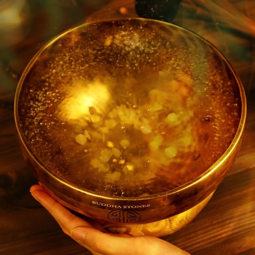 Copper singing bowl held in hand showing brand marking and resonant tone demonstration