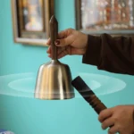 Handcrafted copper singing bowl with wooden mallet striker, hand-held demonstration with sound vibration effect