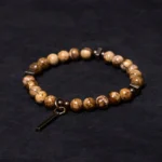 Distressed copper and natural stone Buddhist bracelet with bar pendant displayed on dark fabric background