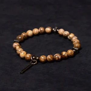 Distressed copper and natural stone Buddhist bracelet with bar pendant displayed on dark fabric background