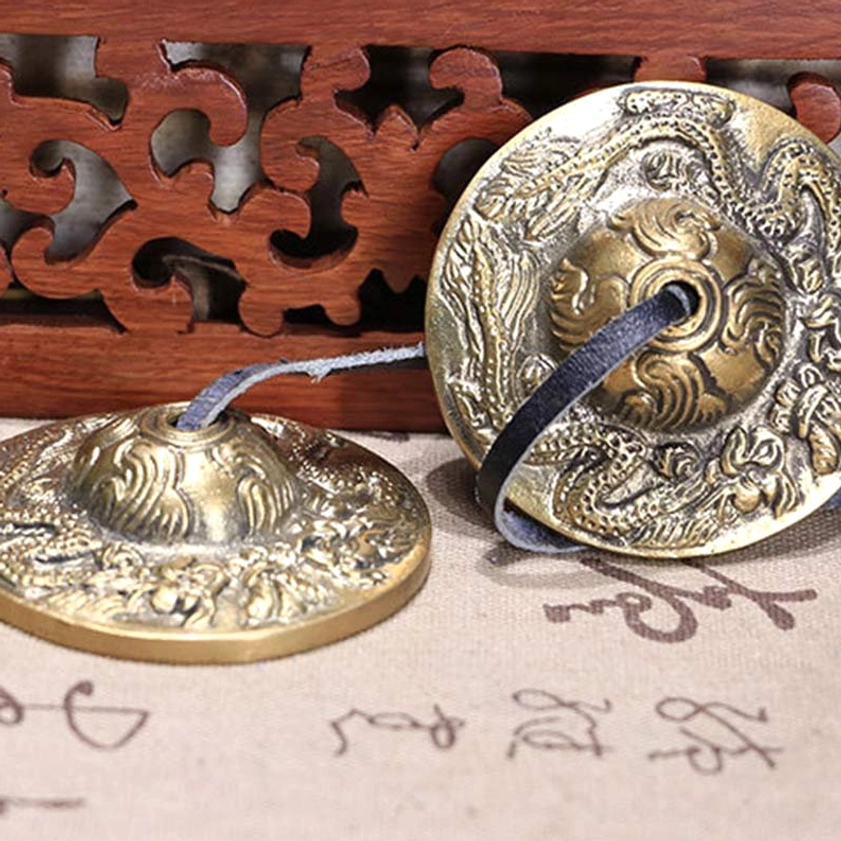 Hand-forged copper tingsha cymbals with traditional Buddhist engravings and leather strap