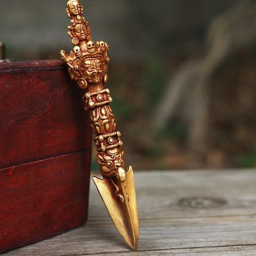 Handmade copper Vajra Dorje ritual object displayed on wooden surface, left oblique view showing intricate carved details and bronze-gold finish