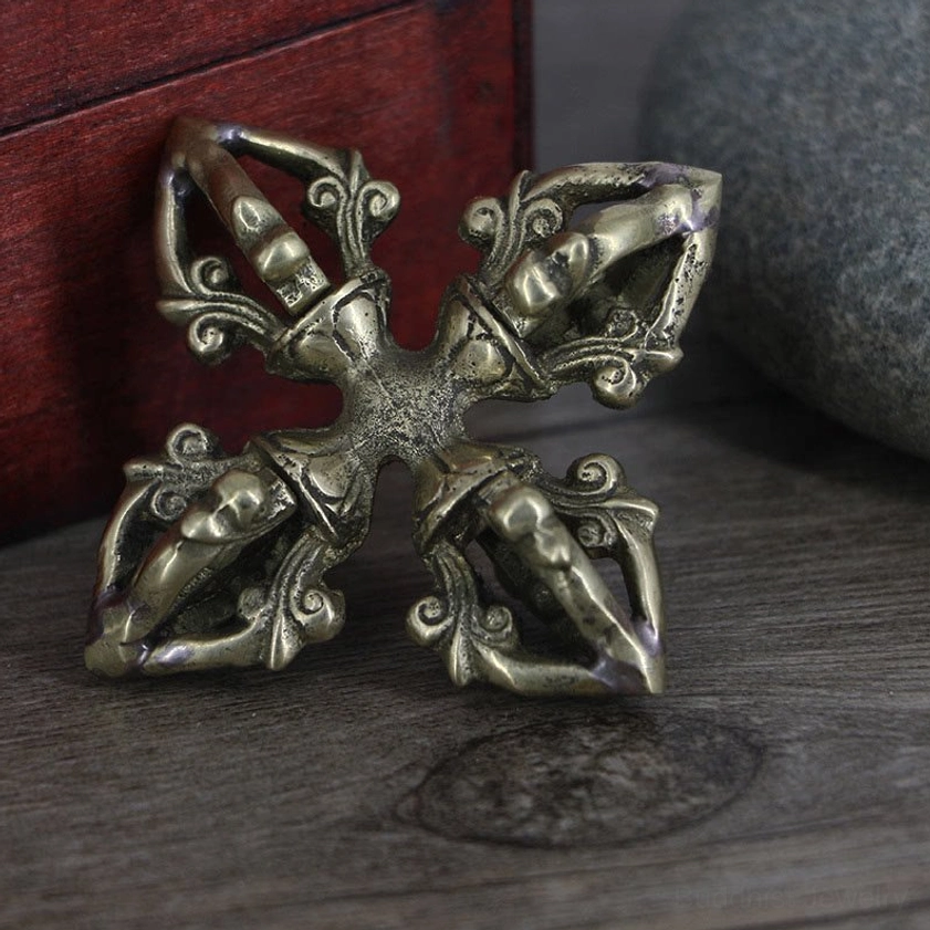 Copper vajra displayed from low side angle with aged bronze finish showing ornate four-pronged structure