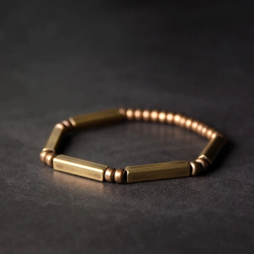 Copper wealth prosperity bracelet top-down flat lay, handcrafted brass beads with geometric design on dark grey background