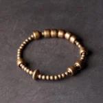 Vintage copper brass beaded bracelet overhead view showing mixed barrel bead design with textured focal bead for wealth and balance