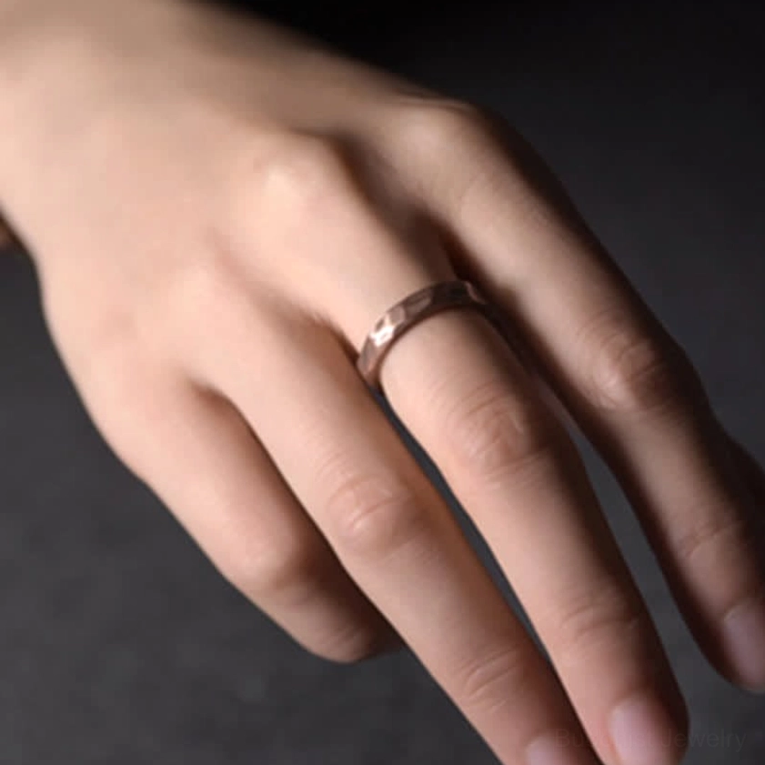 Close-up detail of copper Buddhist wealth ring worn on middle finger showing antique bronze finish