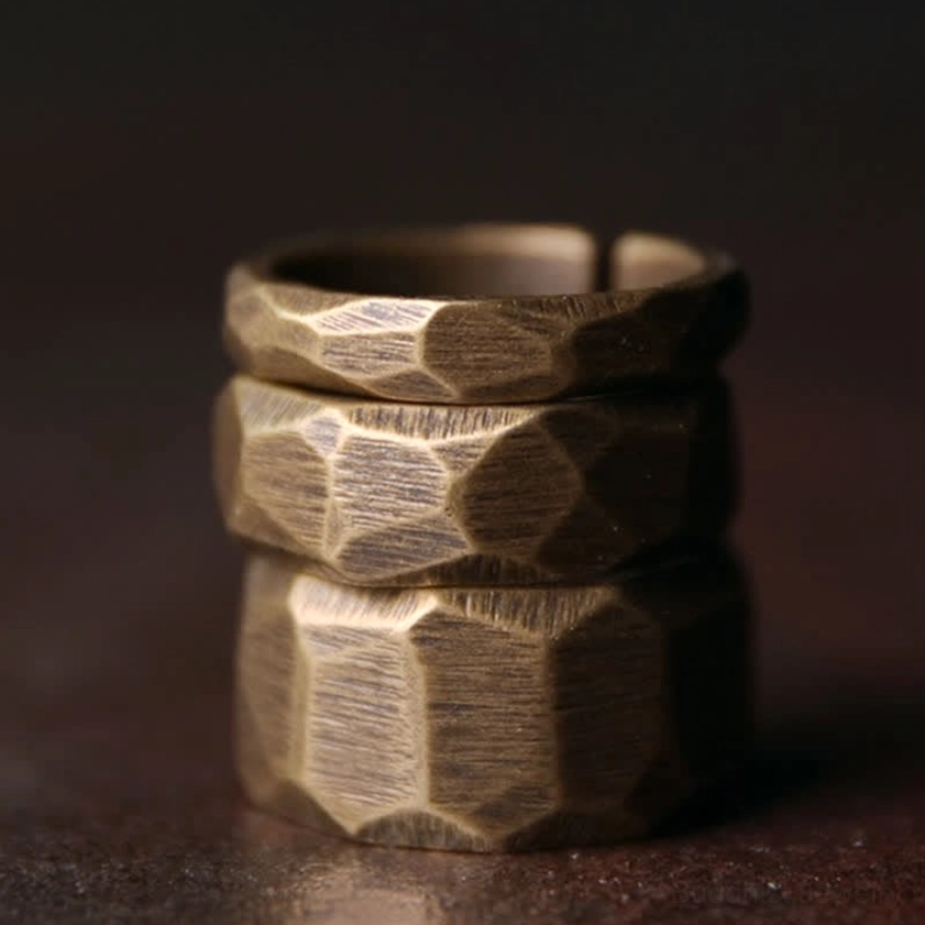 Multiple stacked copper Buddhist wealth rings showing different band widths and warm brass patina finish