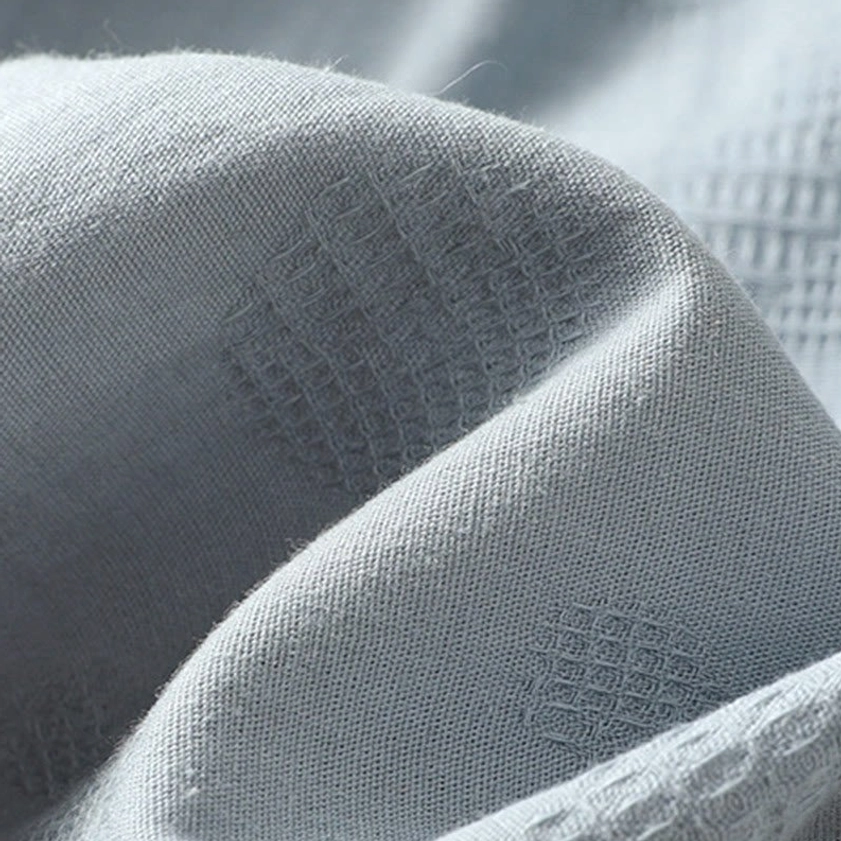 Premium cotton fabric texture close-up - showing embossed grid pattern and softness of meditation clothing