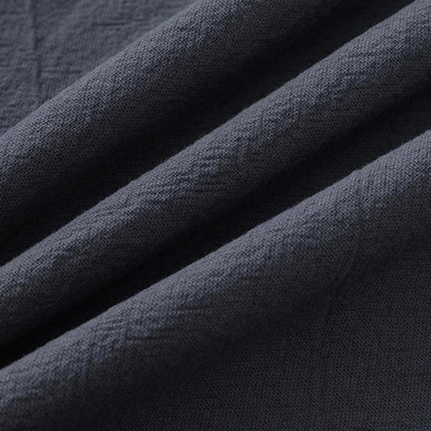 Close-up texture detail of Buddhist meditation clothing - cotton linen blend fabric showing natural breathable weave and wrinkled authentic textile quality