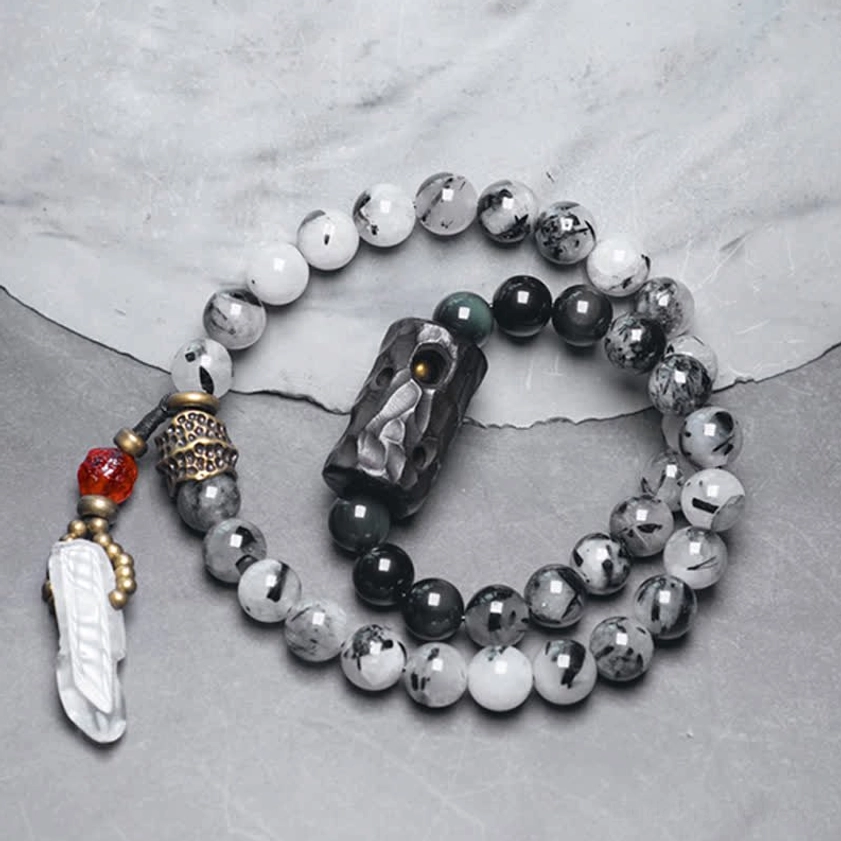 Buddhist couple bracelets with black rutilated quartz and white crystal beads on grey fabric