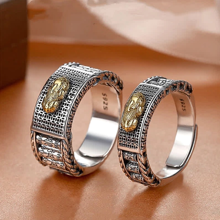 Couple Pixiu wealth rings with gold accents - flat lay on leather showing intricate carved texture, S925 inner mark, adjustable open bands for abundance