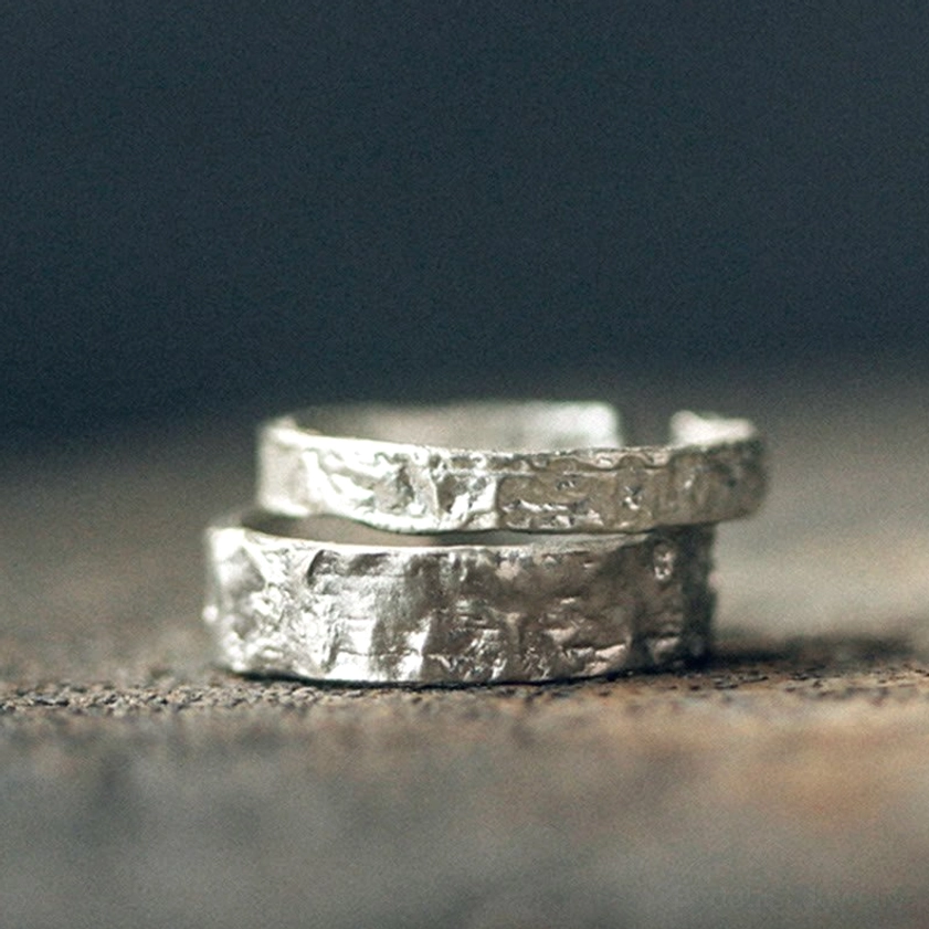 Pair of matching silver rings flat lay with heavy hammered texture and open adjustable bands
