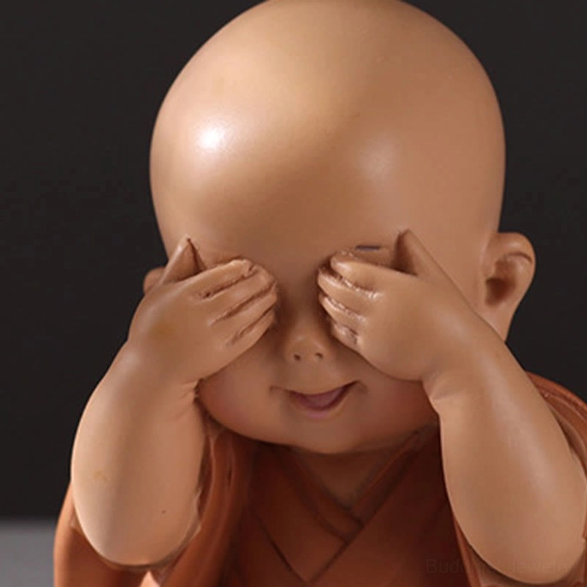 Close-up detail of covering eyes monk figurine showing smiling expression and smooth resin texture