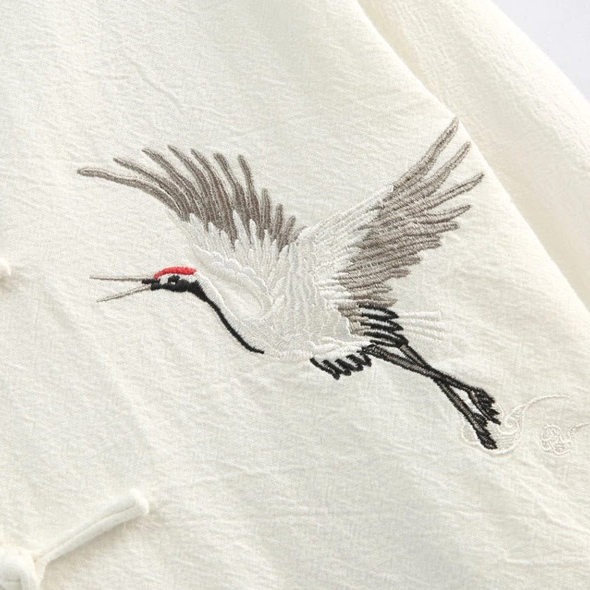 Detailed close-up of red-crowned crane embroidery stitching on linen fabric