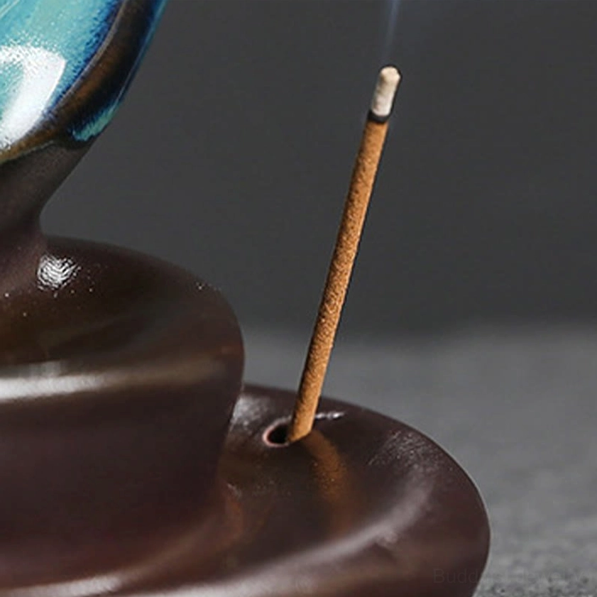 Crescent moon ceramic incense holder with lit candle and flowing backflow smoke, yoga room decor