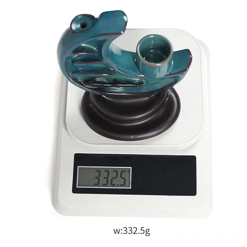 Detail of ceramic crescent moon backflow incense burner showing smoke cascade and candle placement