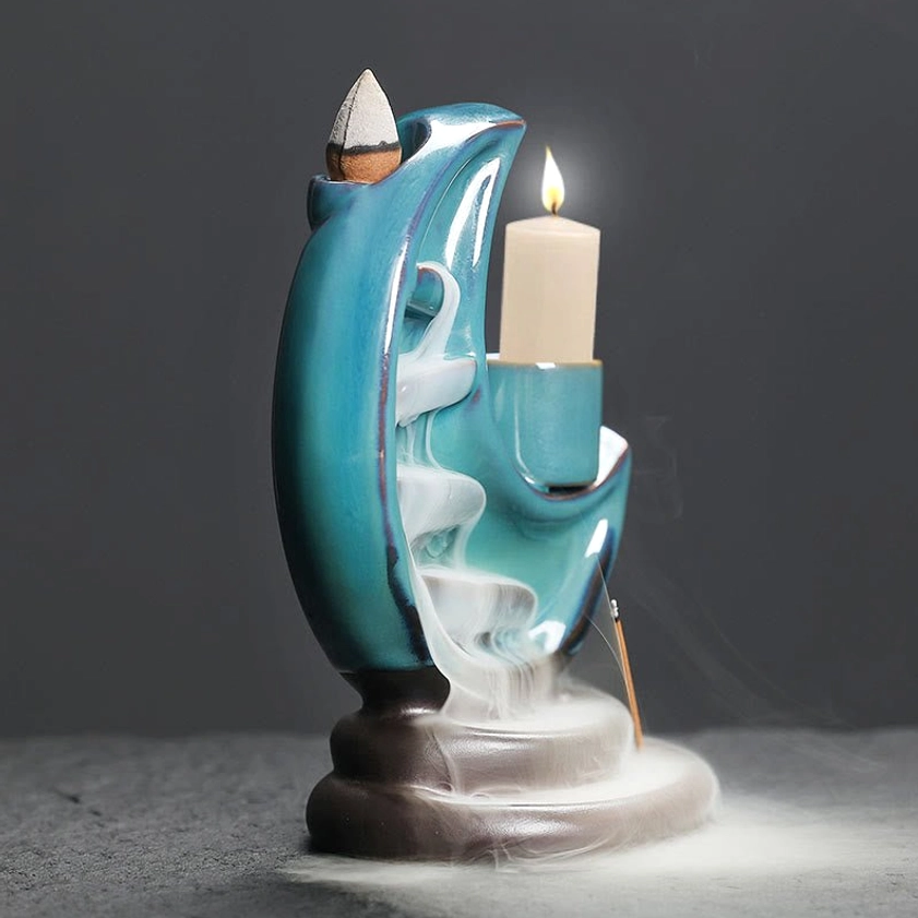 Side view of teal ceramic crescent moon incense burner with visible backflow smoke path and lit candle