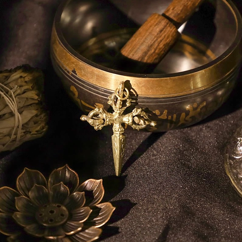Cross vajra with engraved mantra singing bowl in spiritual ritual display set, brass material vajra dorje on dark background