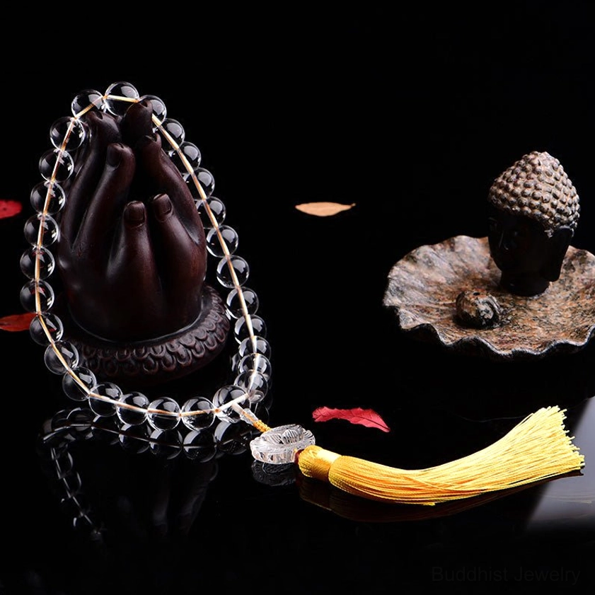 Clear crystal meditation mala beads with Buddha statue and spiritual props, showing Buddhist practice setup