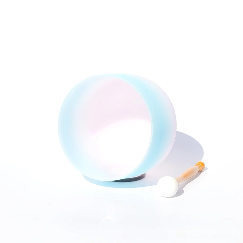 Front profile view of matte white crystal singing bowl with gradient finish, black rubber base, and small wooden mallet